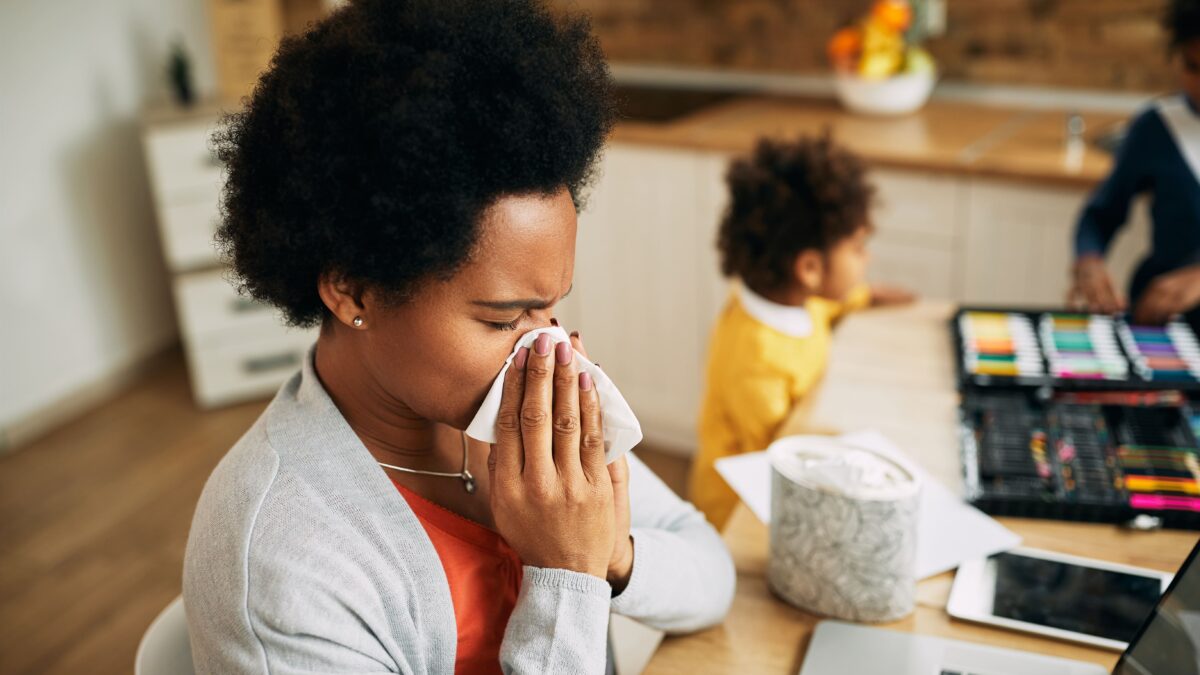 adult woman with cold using tissue indoors