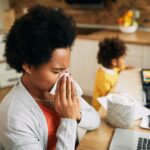 adult woman with cold using tissue indoors