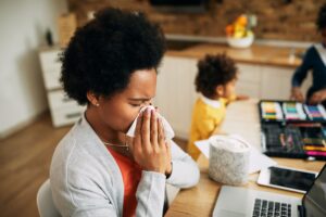 adult woman with cold using tissue indoors