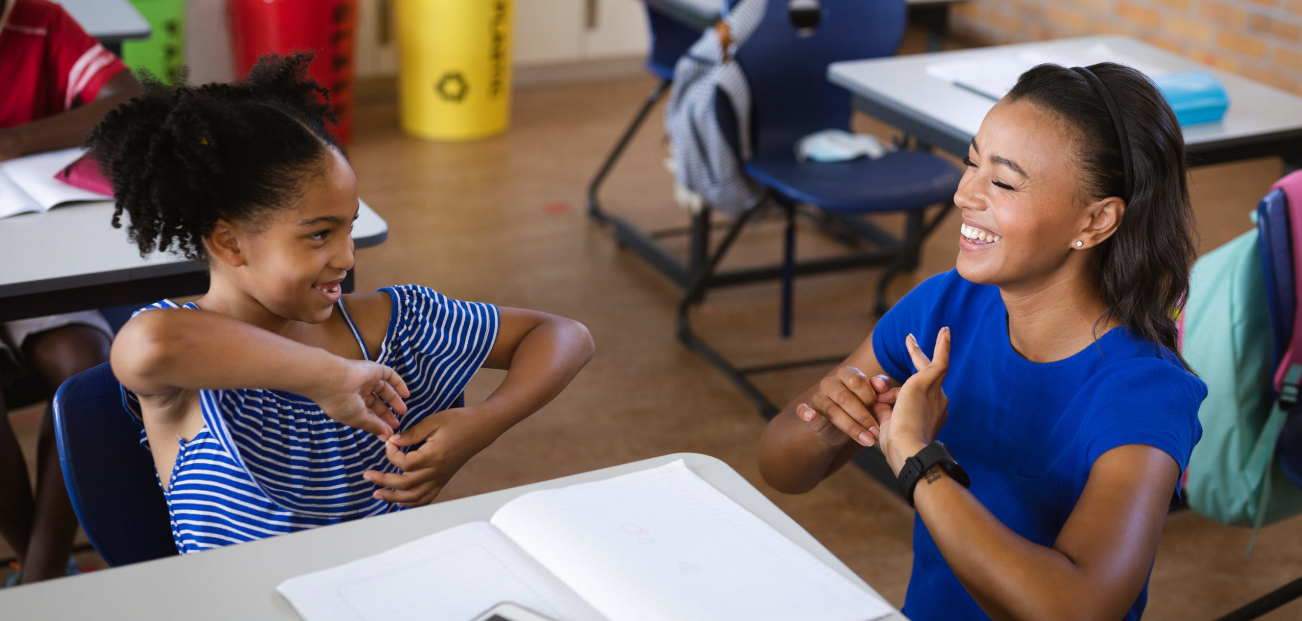 African american female teacher and a girl talking in hand sign language