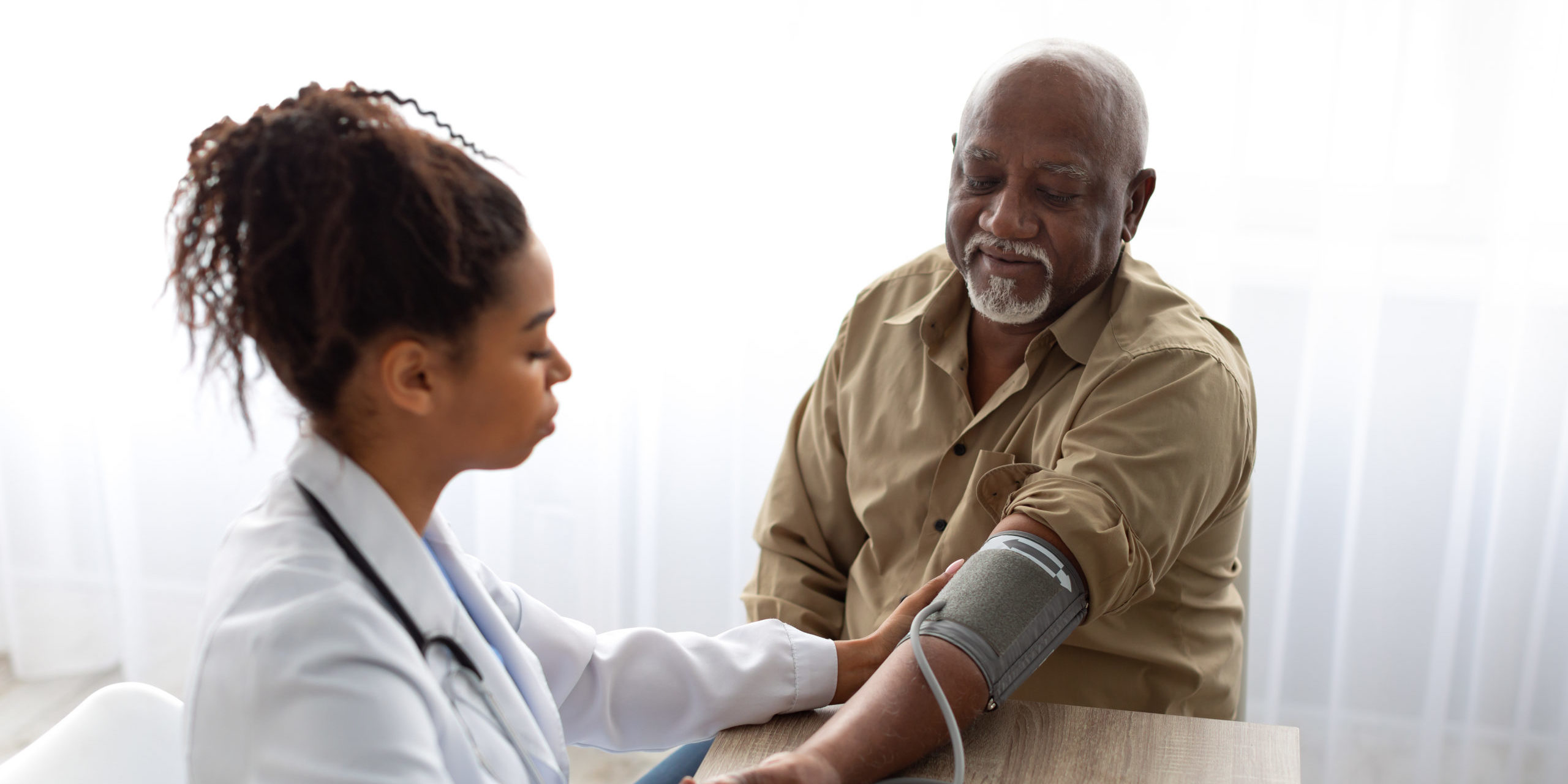 Black female doctor checking measuring pressure on patient's hand