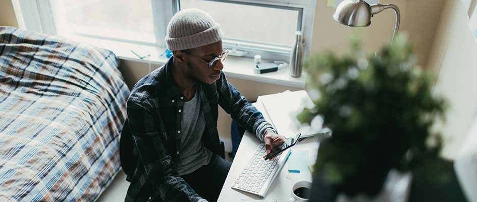 Young man working at his desk in his bedroom.