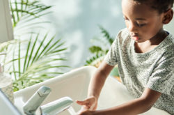 Boy washing his hands at a tap in a bathroom