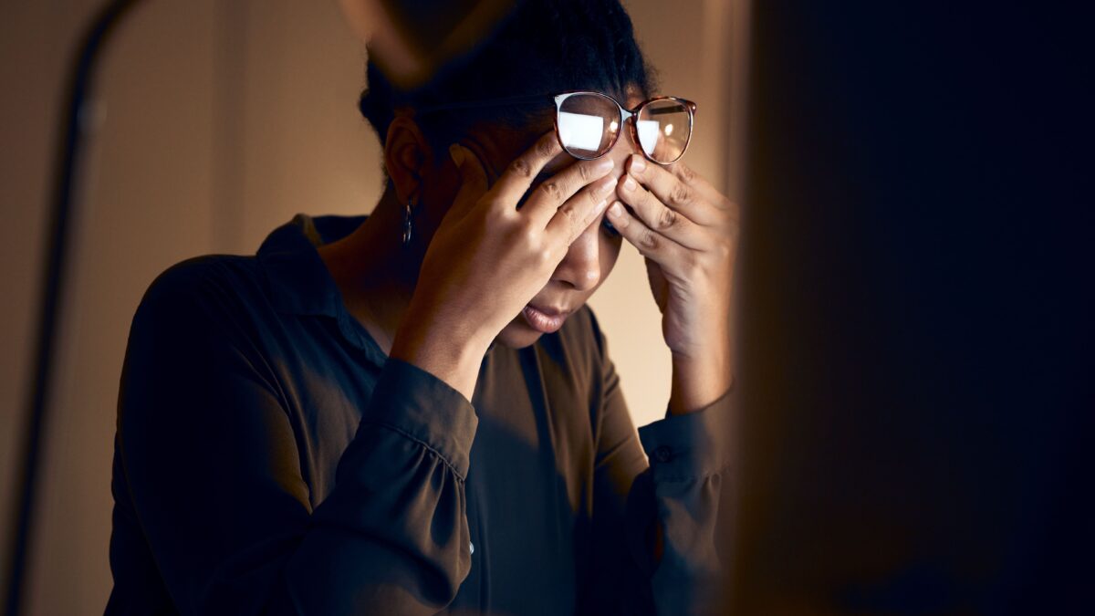 stressed woman with hands on her temples sitting at her desk