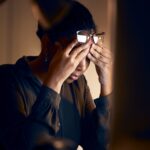 stressed woman with hands on her temples sitting at her desk