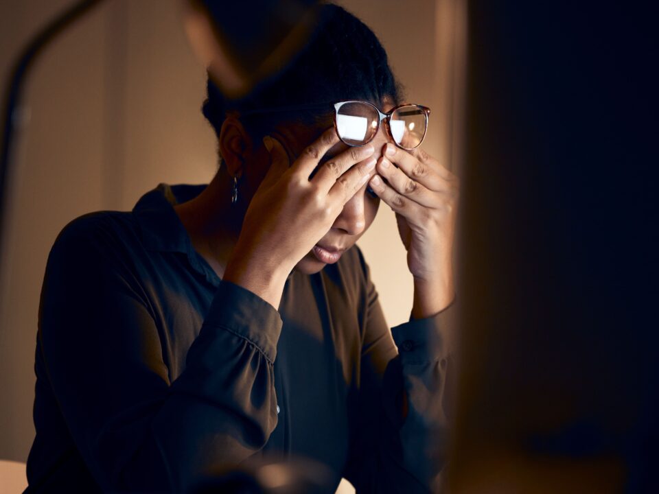 stressed woman with hands on her temples sitting at her desk