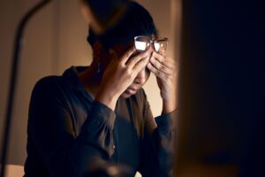 stressed woman with hands on her temples sitting at her desk