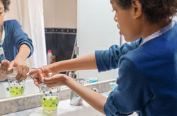 Black boy washing his hands with soap in the bathroom