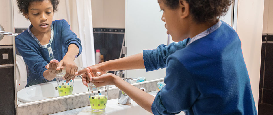 Black boy washing his hands with soap in the bathroom
