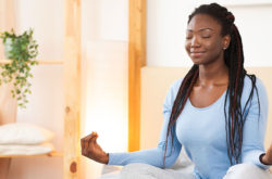 woman meditating on her bed